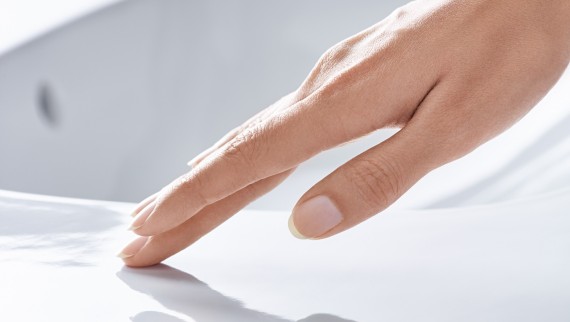 Main passant sur une céramique de lavabo revêtue de l’émail spécial KeraTect® Main passant sur une céramique de lavabo revêtue de l’émail spécial KeraTect®
