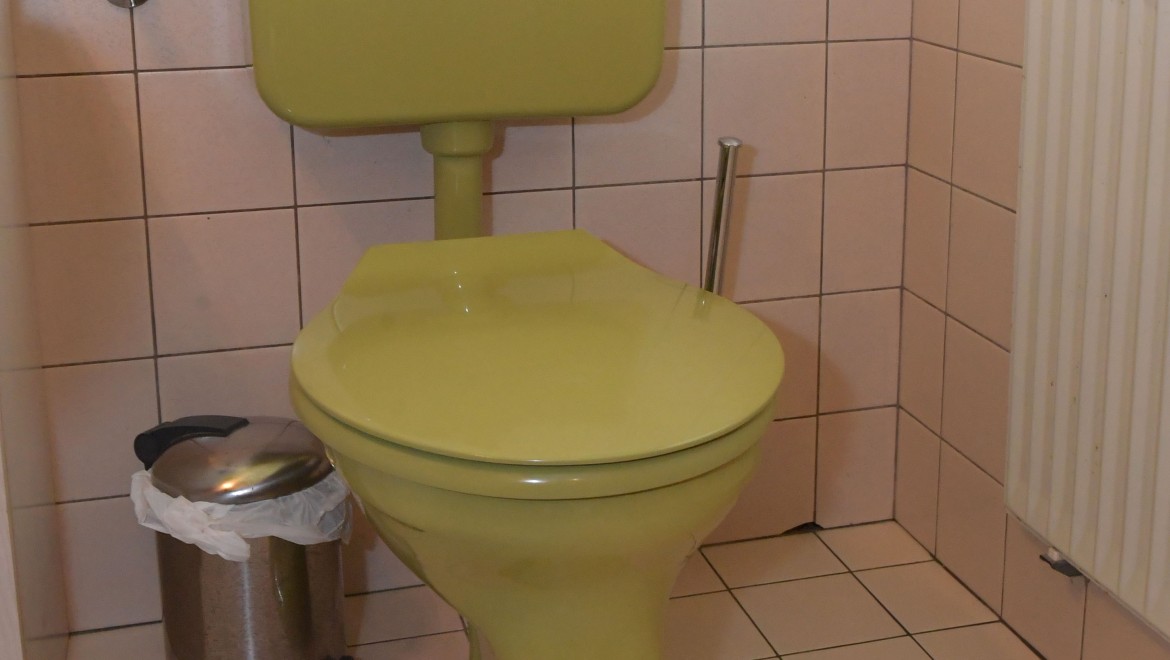 L'ancien WC avec réservoir de chasse apparent dans la salle de bains d'invités